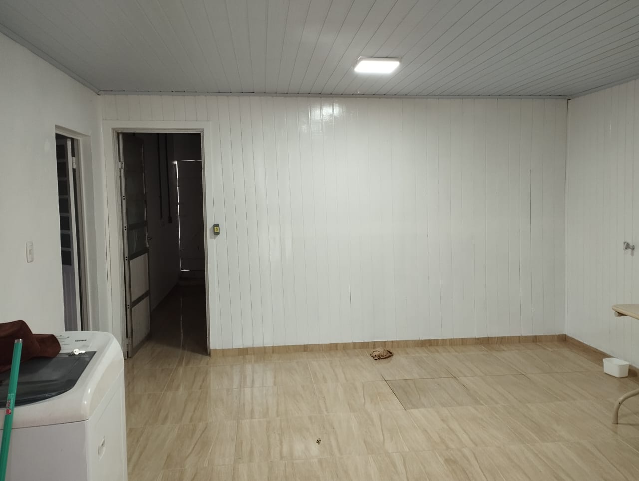 Ambiente interno finalizado com paredes brancas e piso cerâmico